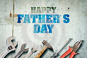 Happy father`s day background. Inscription written on a concrete wall. Tools for repair. Adjustable wrench, hammer, screwdriver