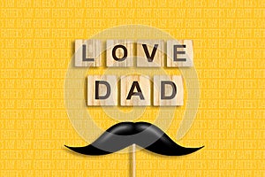 Happy father`s day background. Mustache on a stick. Love Dad, inscription on wooden blocks on a yellow background. Congratulatory