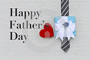 Happy Father`s day card idea, red hear with gift box on men necktie on canvas fabric texture background