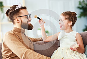 Happy father`s day! child daughter in crown does makeup to daddy
