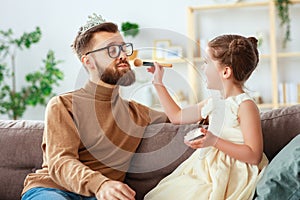 Happy father`s day! child daughter in crown does makeup to daddy