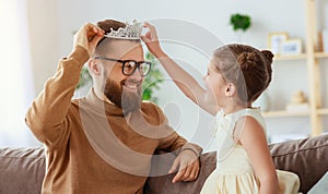 Happy father`s day! child daughter in crown does makeup to daddy