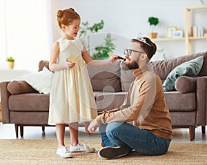 Happy father`s day! child daughter in crown does makeup to daddy