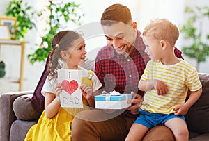 Happy father`s day! Children congratulates dad and gives him gift and postcard
