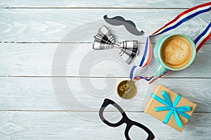 Happy Father`s day concept with coffee cup, competition medal and gift box over wooden background