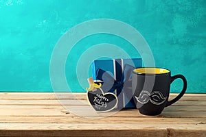 Happy Father`s day concept with coffee mug and gift box over wooden background