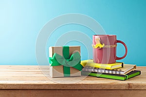 Happy Father\'s day concept with colorful coffee cup, mustache, notebook and gift box on wooden table over blue background