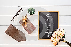 Happy Father`s day concept. Flat lay image of gift box, necktie, glasses, rose flower and notebook with Happy Father\`s Day text