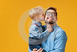 Happy father`s day! cute dad and son hugging on yellow background