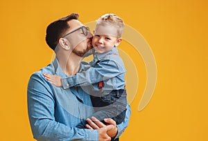 Happy father`s day! cute dad and son hugging on yellow background