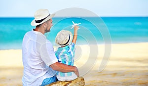 Happy father`s day! dad and child son on beach by sea with model toy plane