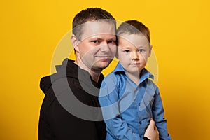 Happy father`s day! Emotional dad and son hugging on yellow background