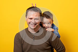 Happy father`s day! Emotional father and son hugging on yellow background