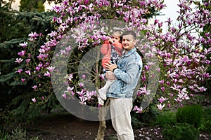 Happy Father\'s Day. Father with daughter in hands enjoying nice spring day near magnolia blooming tree