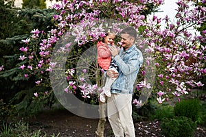 Happy Father\'s Day. Father with daughter in hands enjoying nice spring day near magnolia blooming tree