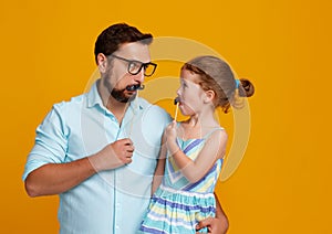 Happy father`s day! funny dad and daughter with mustache fooling