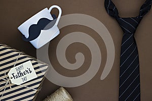 Happy father`s day gift box with a tie and paper mustache on a chocolate background