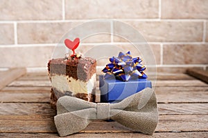 Happy Father`s Day greeting with blue gift box with tiebow and a cupcake decorated with red heart on wooden background