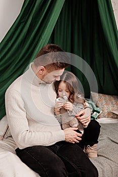 Happy Father& x27;s Day. Young daddy soft embraces his adorable little child daughter at home bedroom on bed. Tender