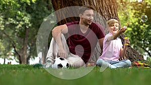 Happy father and son blowing bubbles, having fun together, spending leisure time