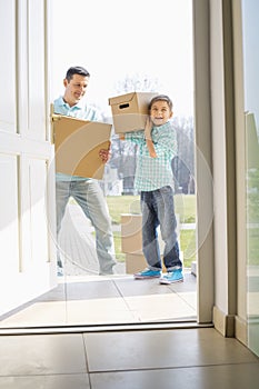 Happy father and son with cardboard boxes entering into new house