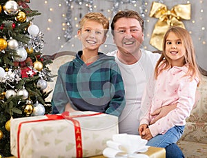 Happy father with son and daughter near the Christmas tree in living room. Merry Christmas