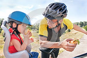 Happy father and son is eating lunch (snack) during bicycle ride