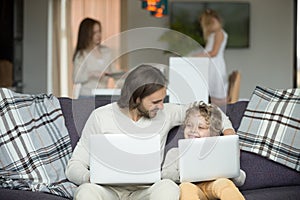 Happy father and son embracing using laptops together at home