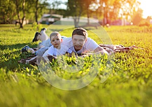 Happy father and son having fun lying on the grass in summer