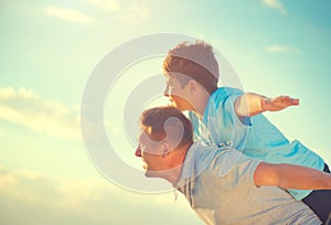 Happy father and son having fun over beautiful sky