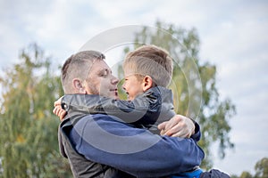 Happy father and son hugging and playing together in green nature. Fisherman`s house with a wooden pedestrian bridge on a tiny