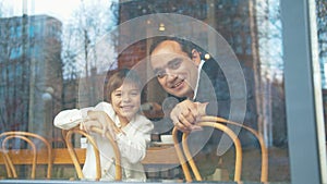 Happy father and son look through the window in a cafe