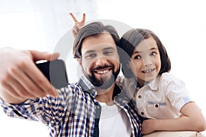 Happy father and son make selfportrait using smartphone.