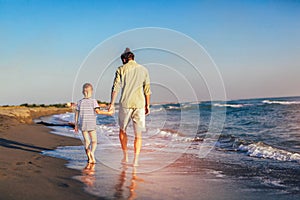 Happy father and son, man & boy child, running and having fun in the sand and waves on the beach