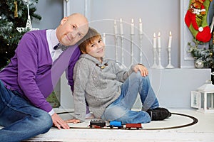 Happy father and son play with toy train near
