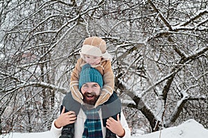 Happy father and son play on winter Christmas time. Father giving son ride on back in park. Portrait of happy father