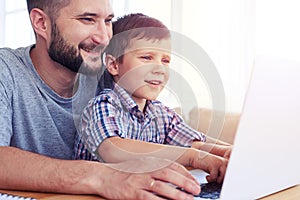 Happy father with son playing computer games on laptop