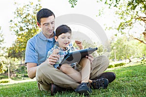 Happy Father and Son Playing on a Computer Tablet Outsdoors