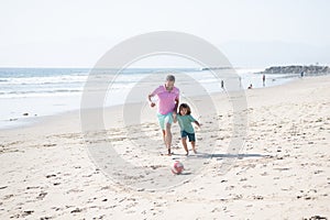 happy father and son playing football having fun on summer sandy beach family vacation, parenthood