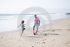 happy father and son playing football having fun on summer sandy beach family vacation, sport