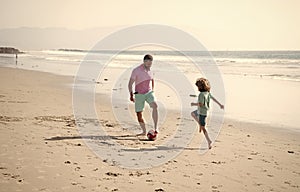 happy father and son playing football having fun on summer sandy beach family vacation, sport