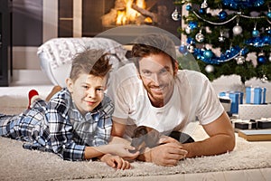 Happy father and son playing with puppy at xmas