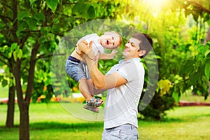 Happy father and son playing together having fun in the green summer park on a warm sunny day. Family and love.