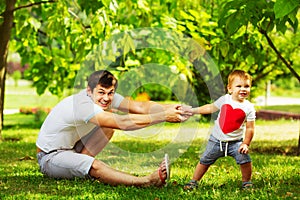 Happy father and son playing together having fun in the green summer park on a warm sunny day. Family and love.