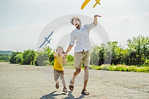 Happy father and son playing with toy airplane against old runway background. Traveling with kids concept