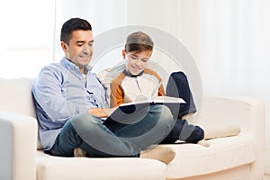 Happy father and son reading book at home