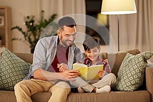 Happy father and son reading book sofa at home