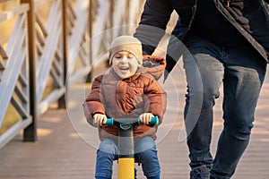 Happy father and son ride a bicycle on a bridge on a sunny day.
