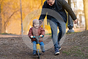 Happy father and son ride a bicycle in a park on a sunny day.