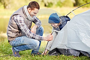 Happy father and son setting up tent outdoors